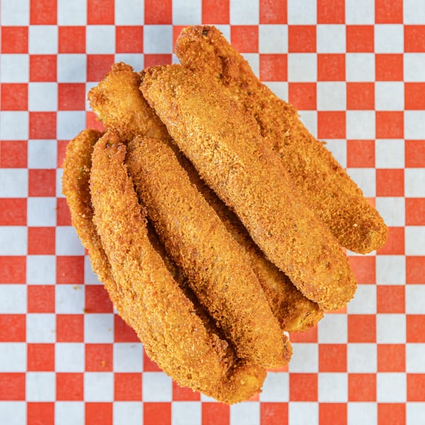 Golden-brown fried chicken tenders, seasoned with spices, arranged on red and white checkered paper.